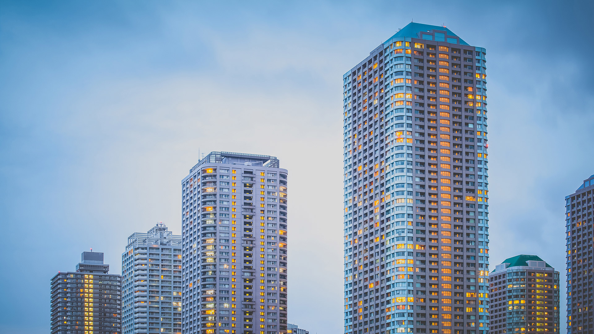 High-rise residential apartment buildings at dusk with illuminated windows against evening sky