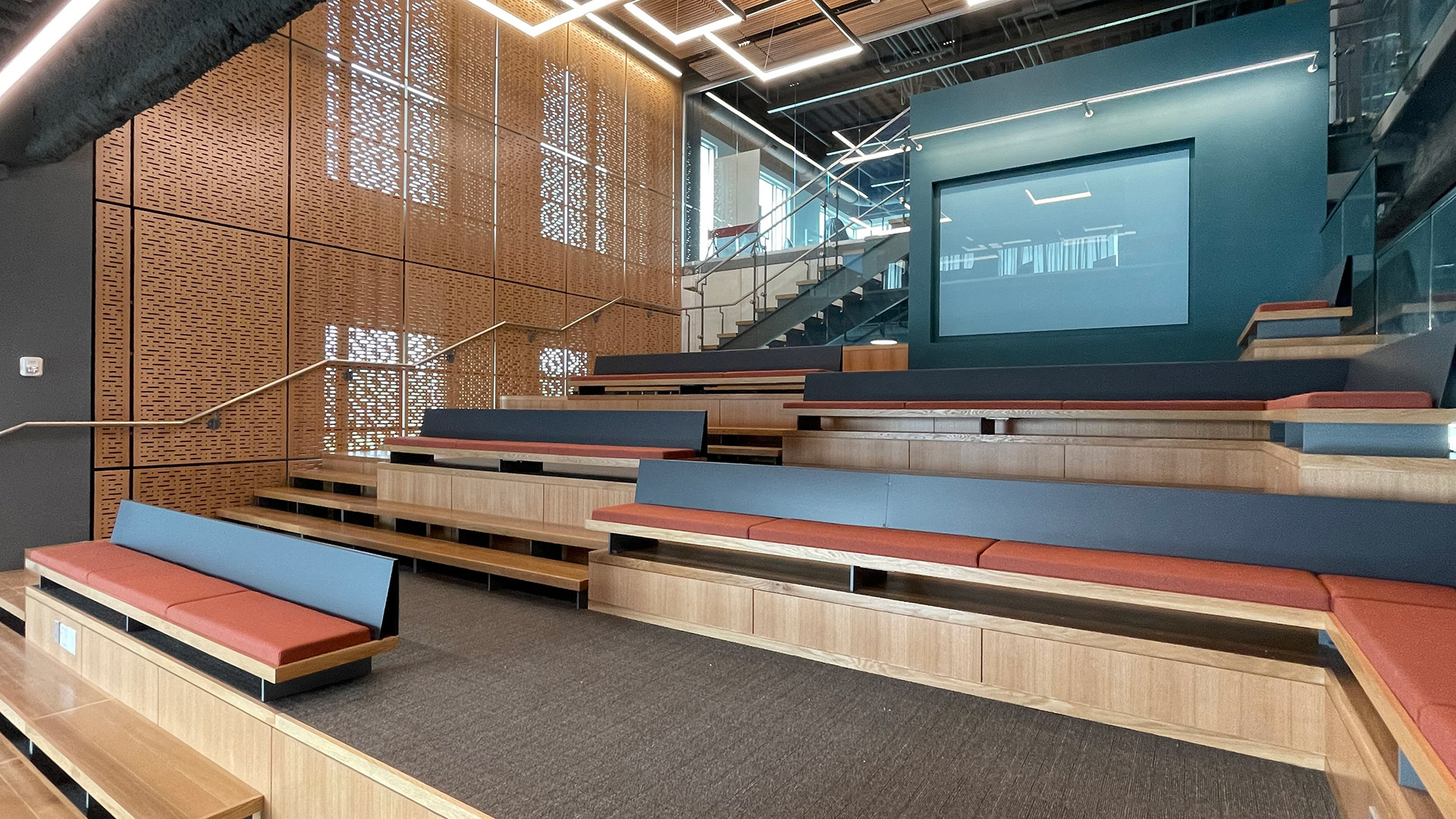 Two-story open forum with tiered wood seating and assembly stair inside the University of Delaware FinTech Innovation Hub fit-out renovation on the STAR Campus