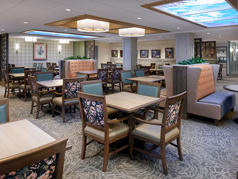 Renovated dining room at Kendal at Longwood with updated lighting, booth seating, and modern finishes