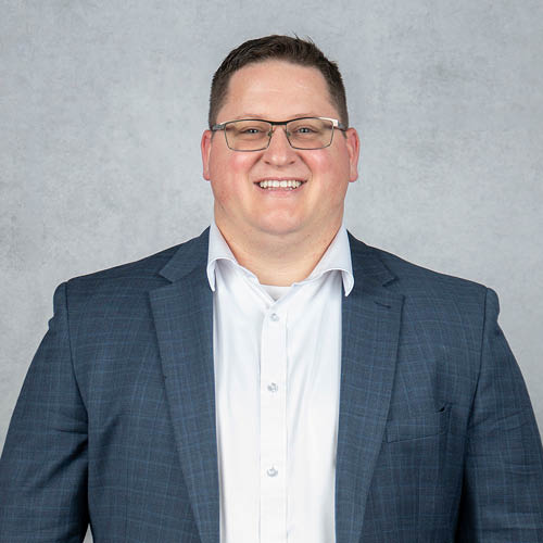 Connor D. Smith professional headshot in business attire, smiling confidently against a neutral studio background.