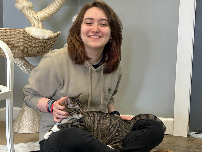 Isabella smiling while holding a tabby cat indoors.