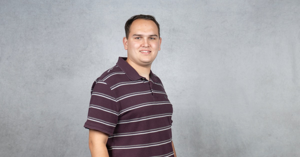 Aidan G. Berkey smiling in a professional headshot against a gray studio background.